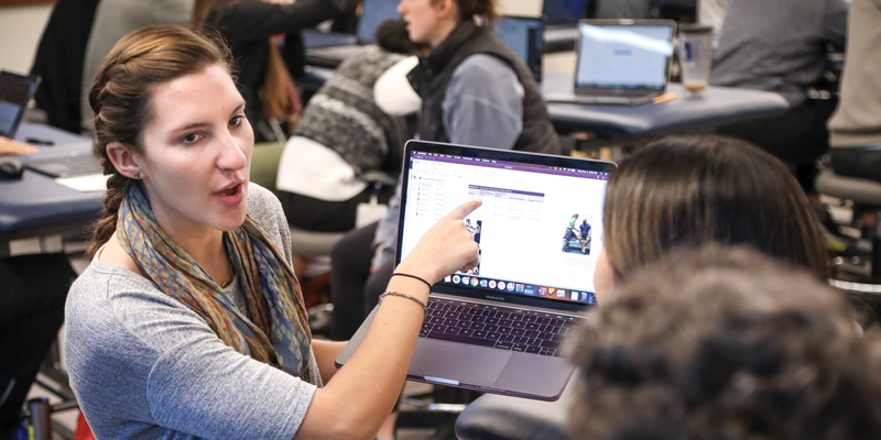 A woman points at a computer screen