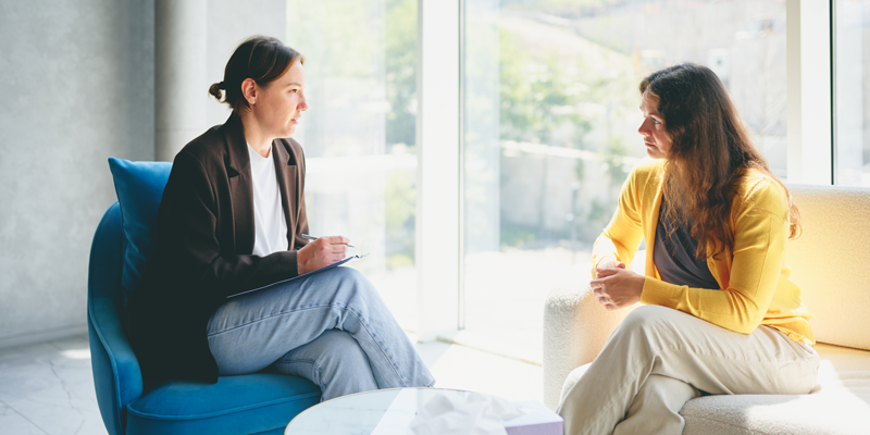 Two women talking in a sun-filled room